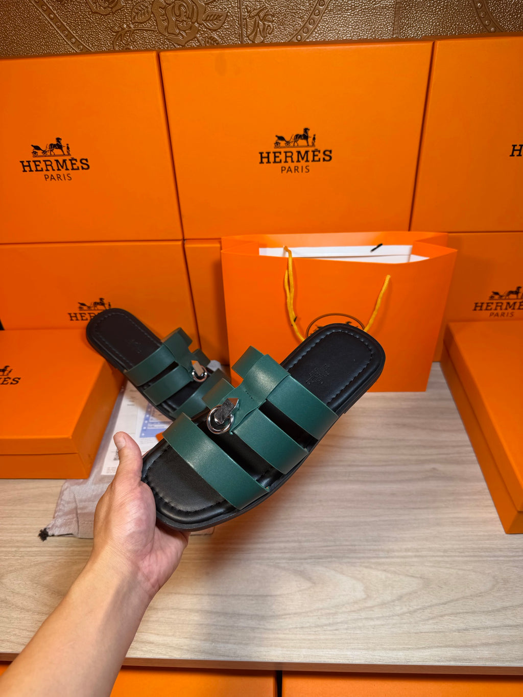 Hermes green leather slide sandal held in hand, two straps with silver buckle