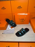 Hermes green leather slide sandals, one sandal shown on top of another