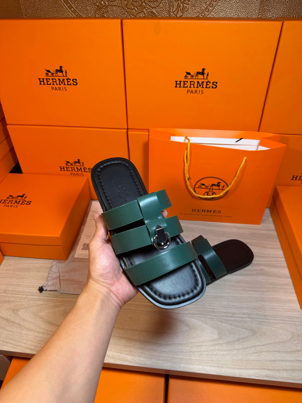 Hermes green leather sandal held in hand, cushioned sole and silver buckle