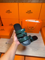 Hermes green leather sandal held in hand, cushioned sole and silver buckle