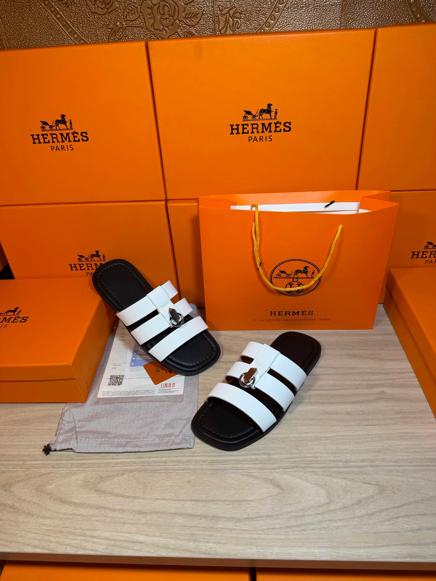 Luxury Hermes sandals displayed: white striped straps over black footbeds with silver buckle.