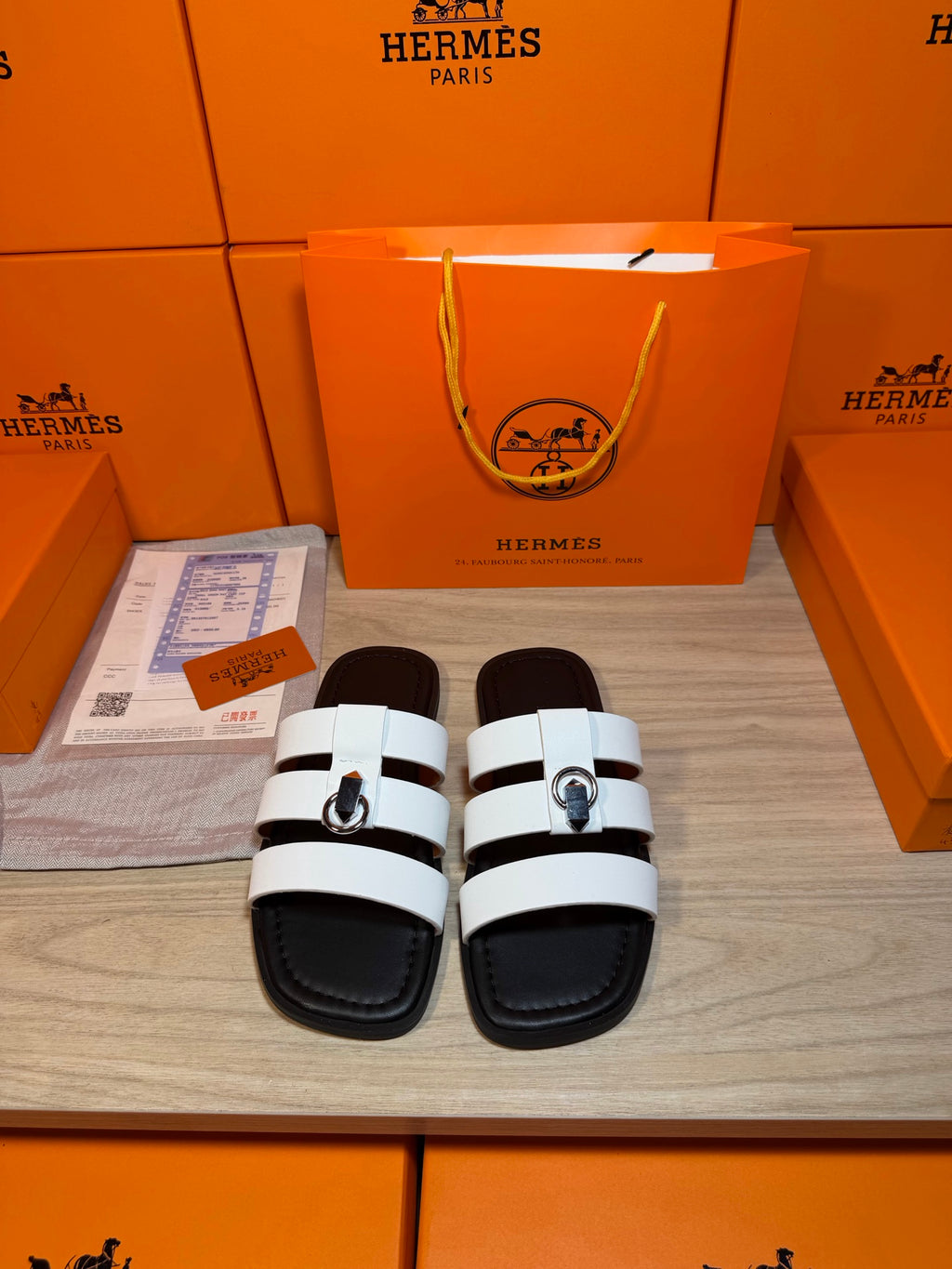 Luxury Hermes sandals with black sole and white leather-look straps, silver buckle.