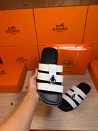 Luxury Hermes sandal held up with two white straps and silver buckle on black sole.
