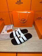 Luxury Hermes sandals, white banded straps on black slides with a silver buckle.