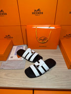 Luxury Hermes sandals with white contrast straps and silver buckle, angled side view.