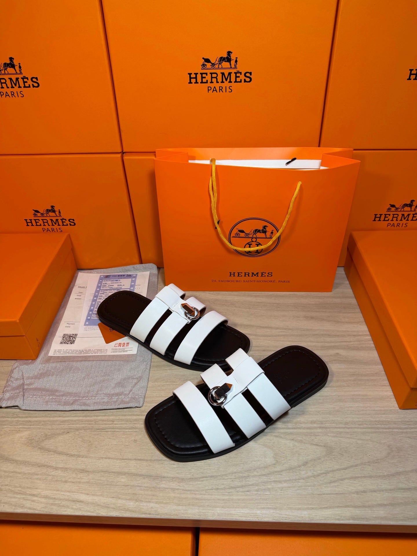 Luxury Hermes sandals with white contrast straps and silver buckle, angled side view.