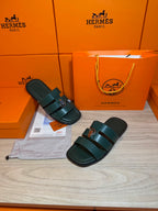 Teal leather slide sandals with two straps and silver buckle, pair on display