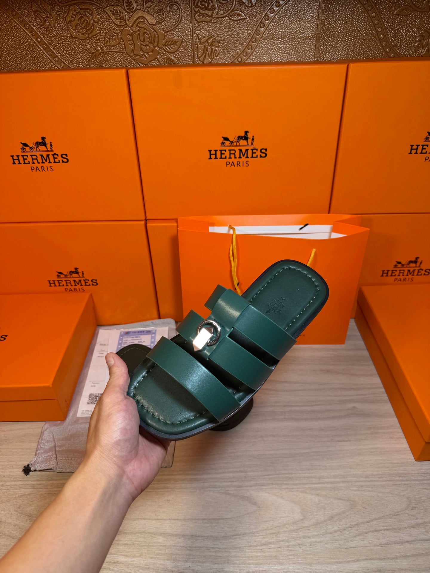 Teal leather slide sandal with two wide straps and silver buckle, held in hand