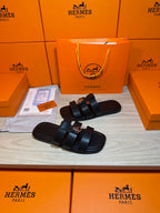 Dark leather slide sandals with two wide straps and round metal buckle hardware