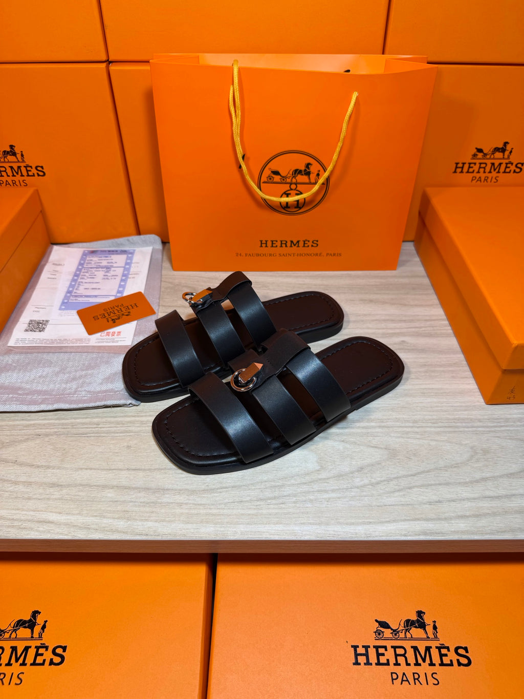 Pair of dark leather Hermes slide sandals with two wide cross straps and buckle