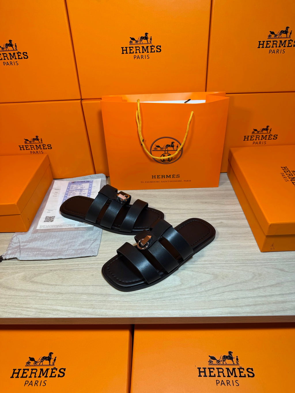 Leather Hermes slide sandals with two dark padded straps and metal buckle on strap