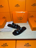 Leather Hermes slide sandals with two dark padded straps and metal buckle on strap