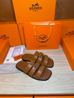Brown leather slide sandals with two wide straps and silver buckle detail.