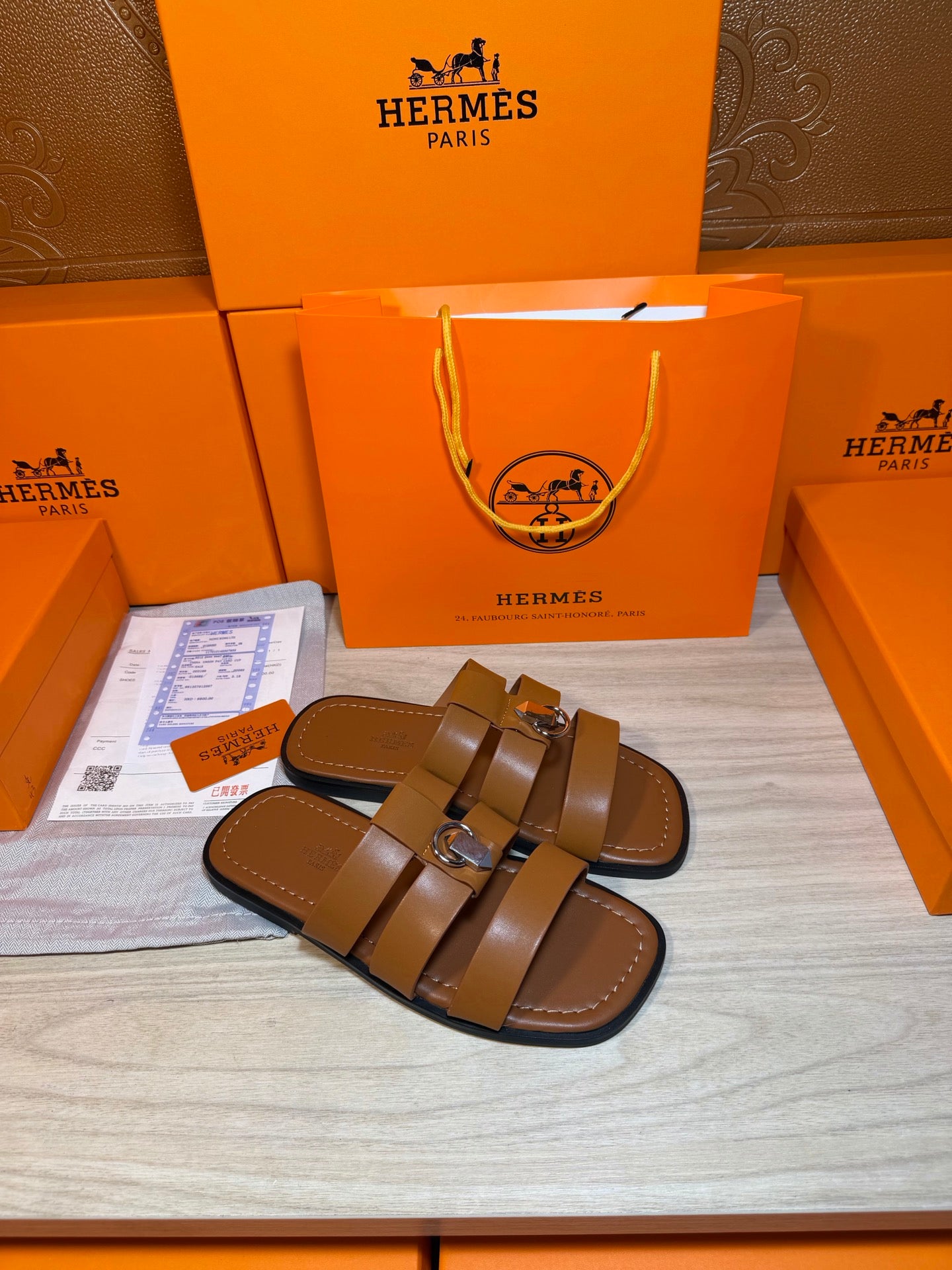 Brown leather slide sandals with two wide straps and silver buckle detail.