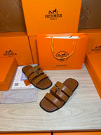 Brown leather sandals with two wide straps and silver buckle, side-by-side view.
