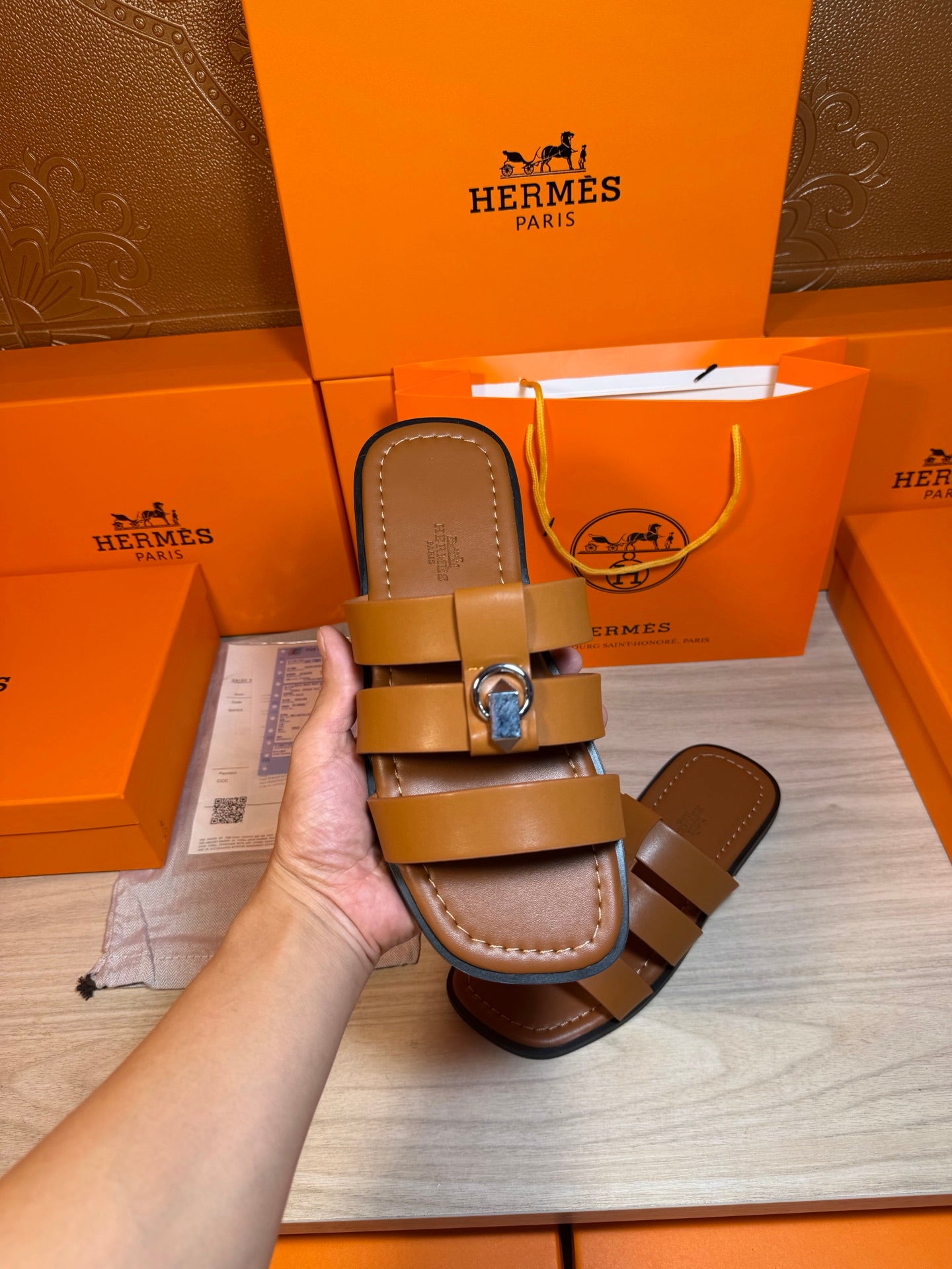 Brown leather sandals in hand, tan footbed with two straps and silver buckle.