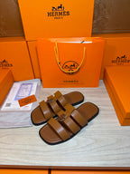 Brown leather sandals with two straps and silver buckle, angled side view.