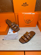 Brown leather sandals with two wide straps and silver buckle, single and pair.