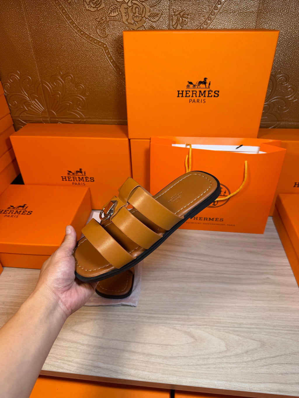 Brown leather sandals in hand, double strap design with silver buckle.