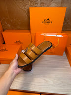 Brown leather sandals in hand, double strap design with silver buckle.