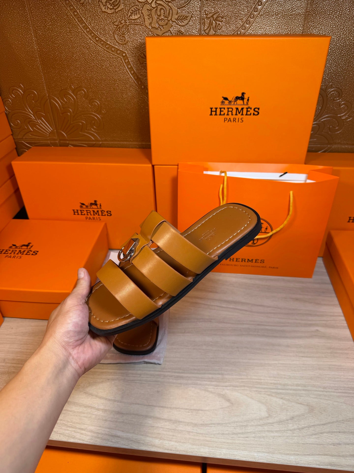 Brown leather sandals in hand, double strap design with silver buckle.