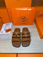 Brown leather sandals with two wide straps and silver buckle, front pair view.