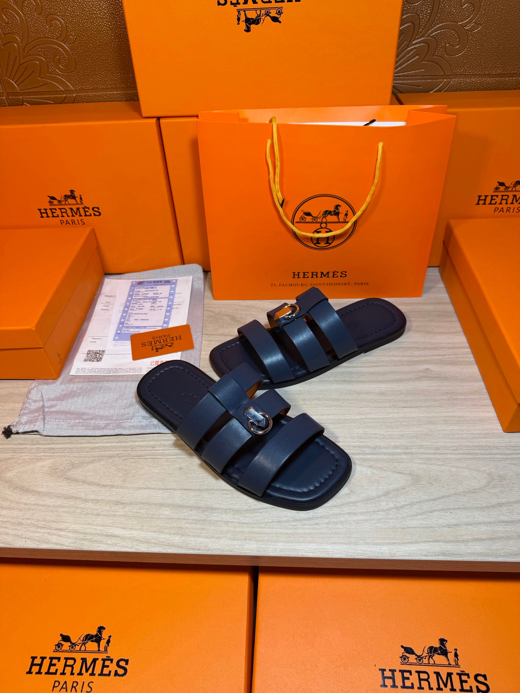 Dark blue leather slide sandals with two straps and a metal buckle at the top