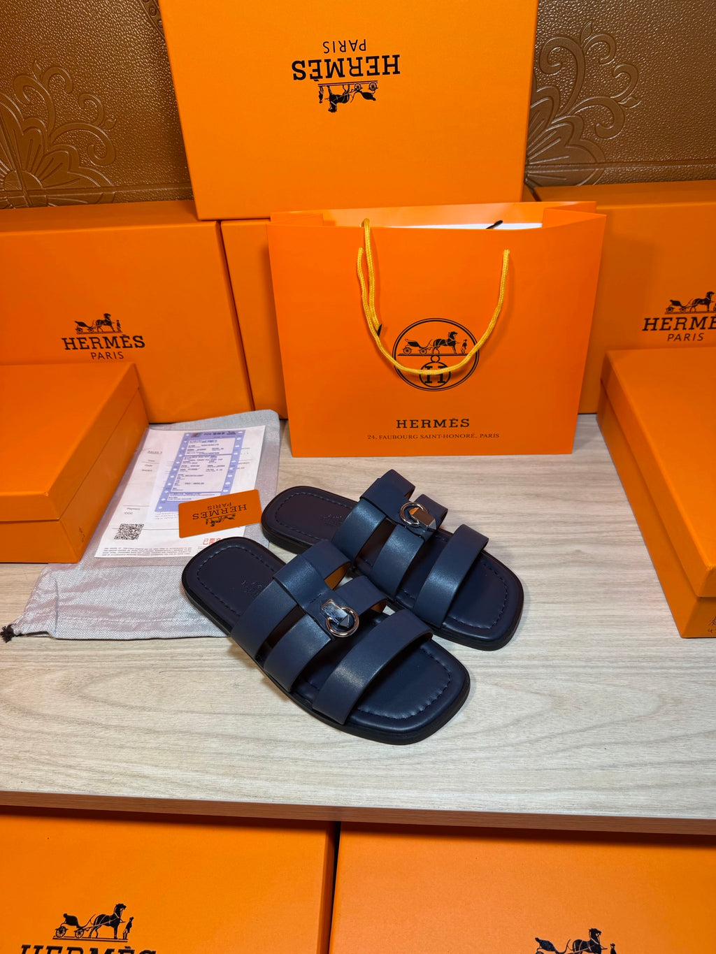 Pair of dark blue slide sandals with double straps and metal buckle details