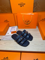 Pair of dark blue slide sandals with double straps and metal buckle details