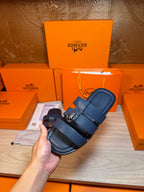 Dark blue leather slide sandal held near the footbed and double strap buckle