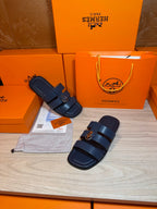 Two dark blue slide sandals with wide straps and metal buckle on the top
