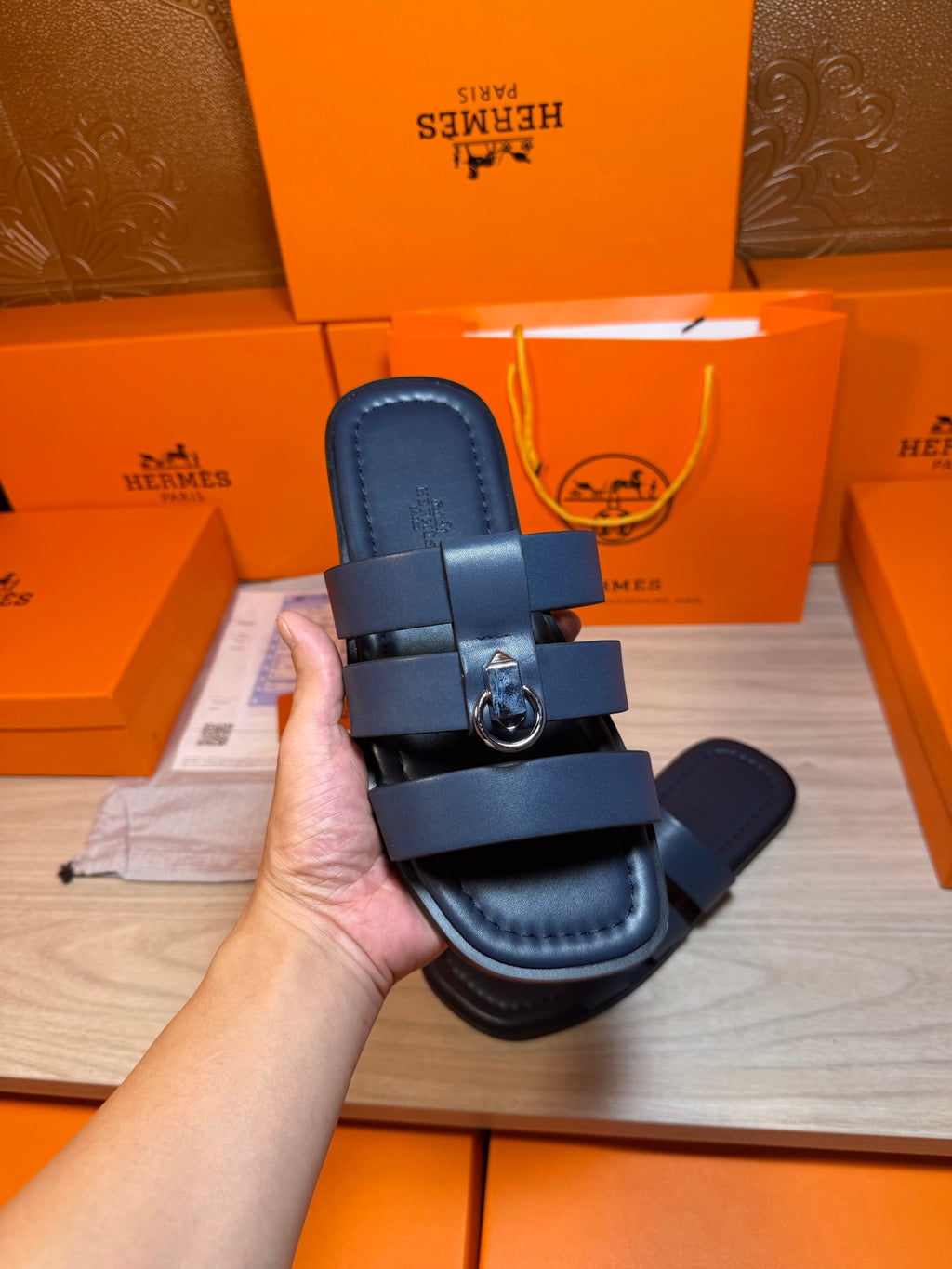 Dark blue slide sandal held up, showing footbed and strap with metal buckle