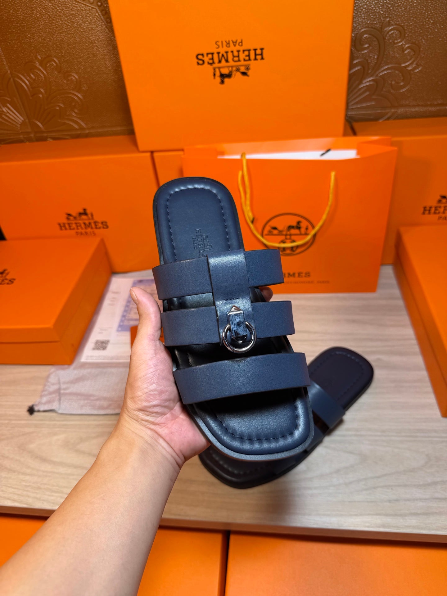 Dark blue slide sandal held up, showing footbed and strap with metal buckle