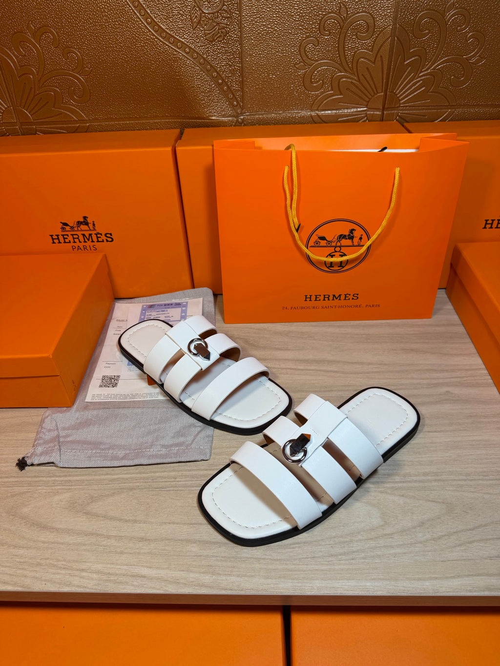 Hermes white leather slide sandals on display with double straps and silver buckle