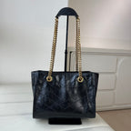 Black leather tote with quilted front, gold chain handles, and YSL center logo