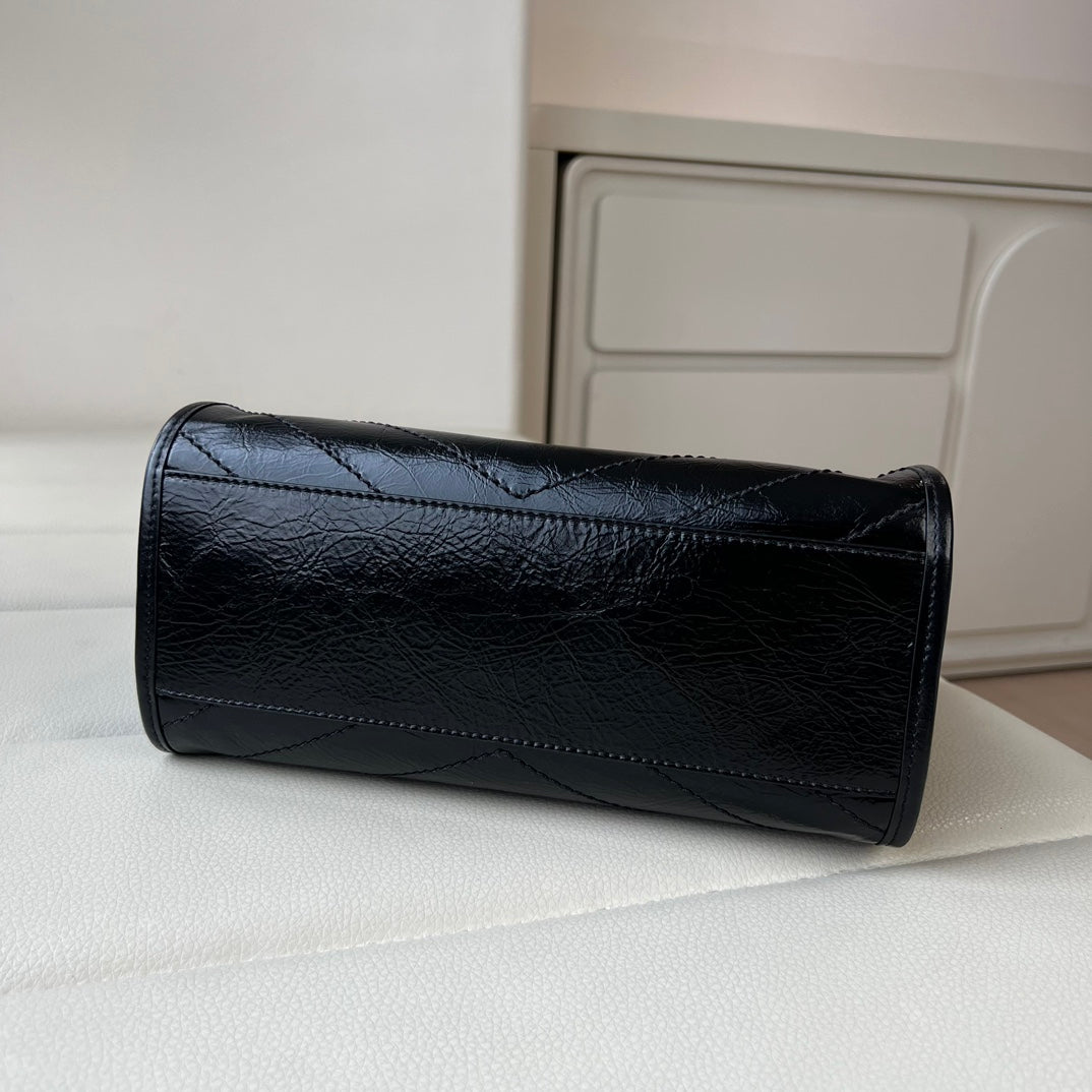 Black leather tote bag back view with quilted texture and top border