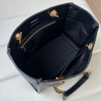 Black leather tote bag interior with open top, side pockets, and gold hardware