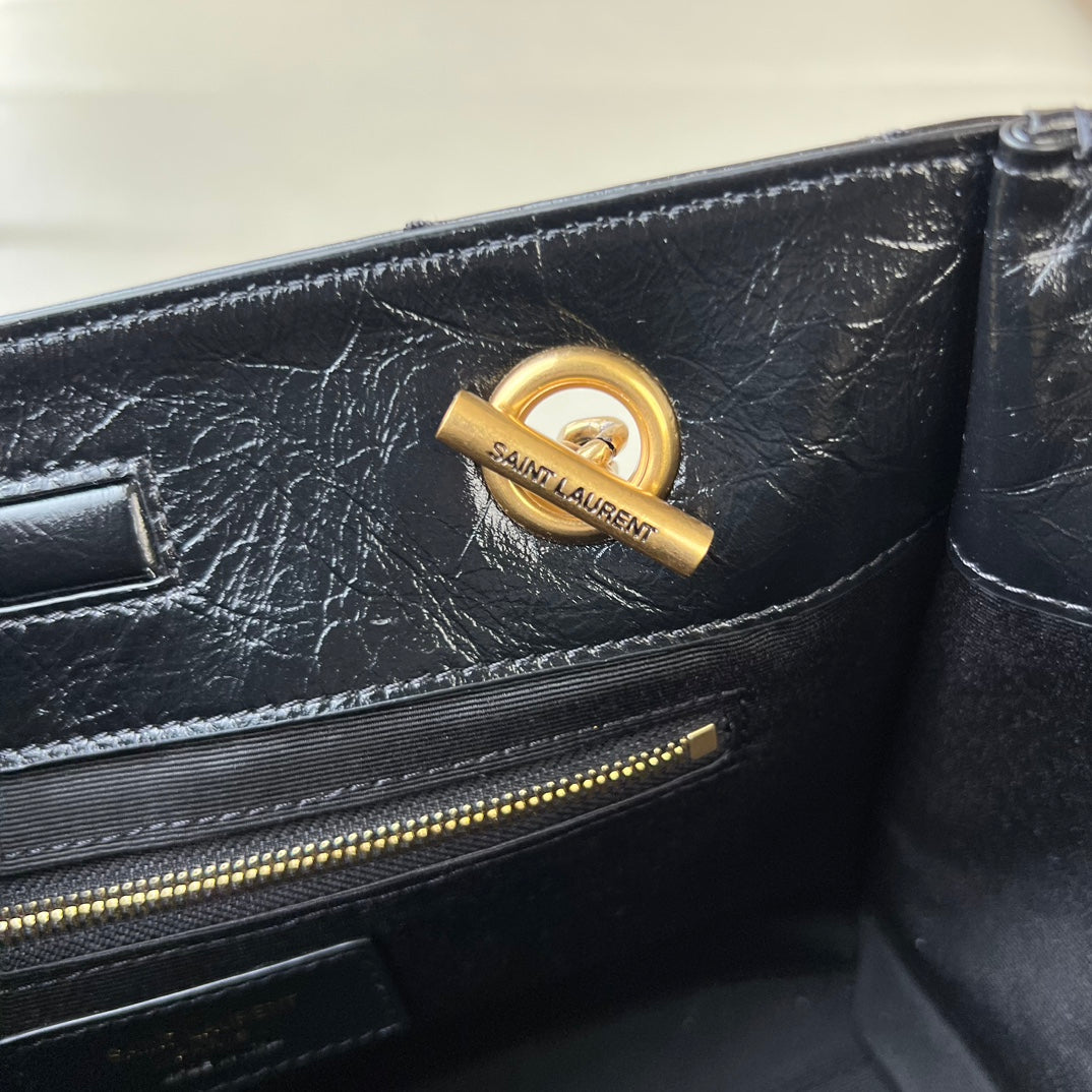 Black leather tote bag with gold YSL logo charm on front panel