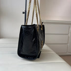 Black leather tote bag with gold chain handles and structured side pocket