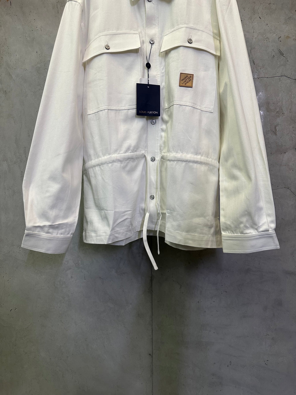 White long-sleeve button-up jacket front with flap pockets and drawstring hem