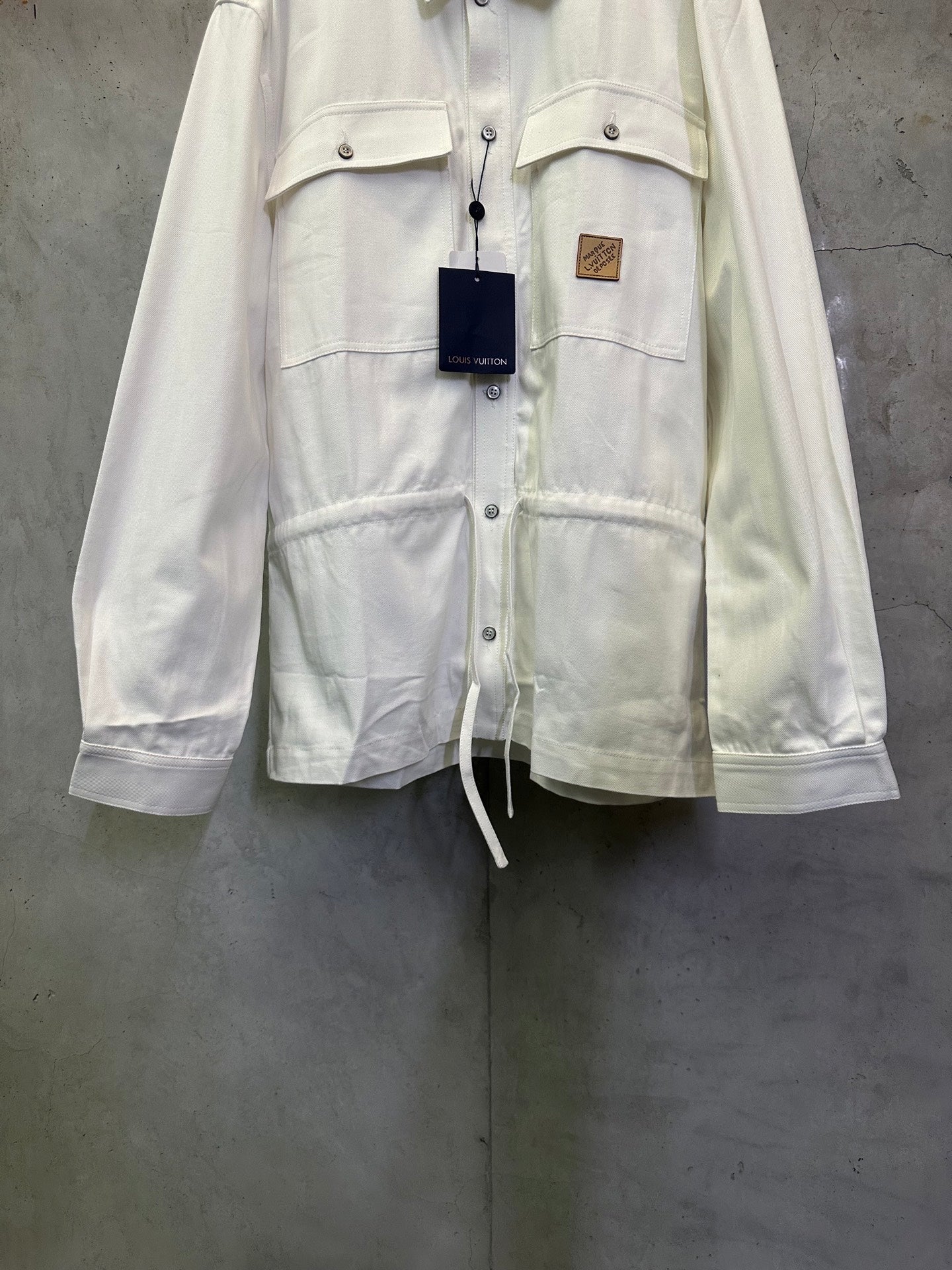 White long-sleeve button-up jacket front with flap pockets and drawstring hem