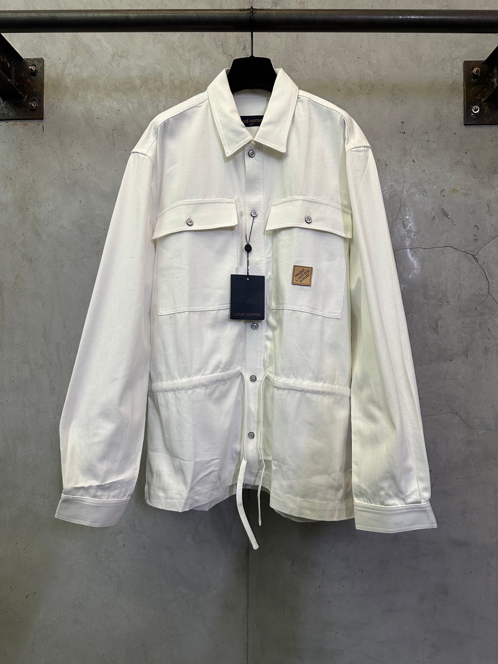 White long-sleeve button-up jacket with flap chest pockets and drawstring hem