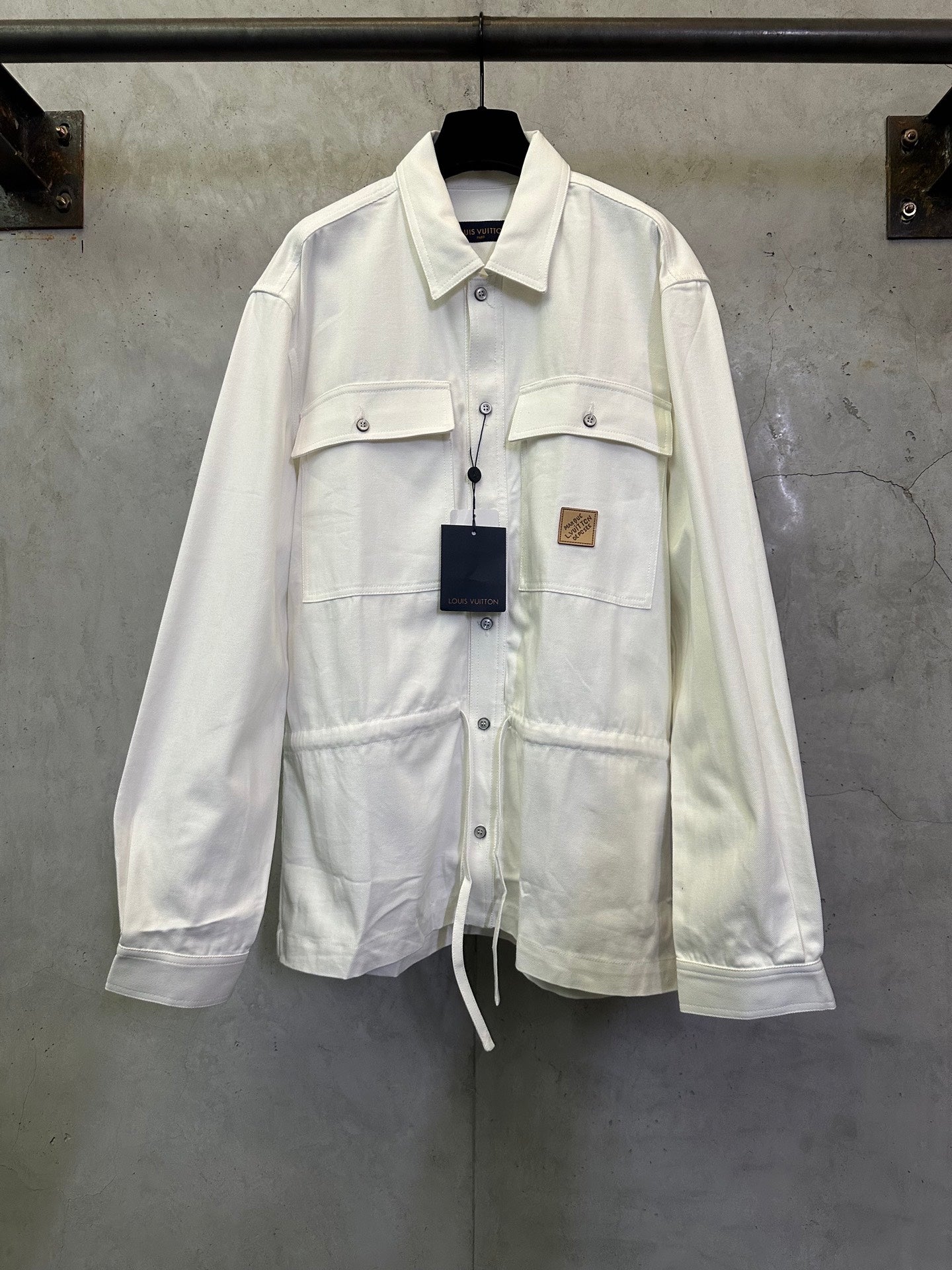 White long-sleeve button-up jacket with flap chest pockets and drawstring hem