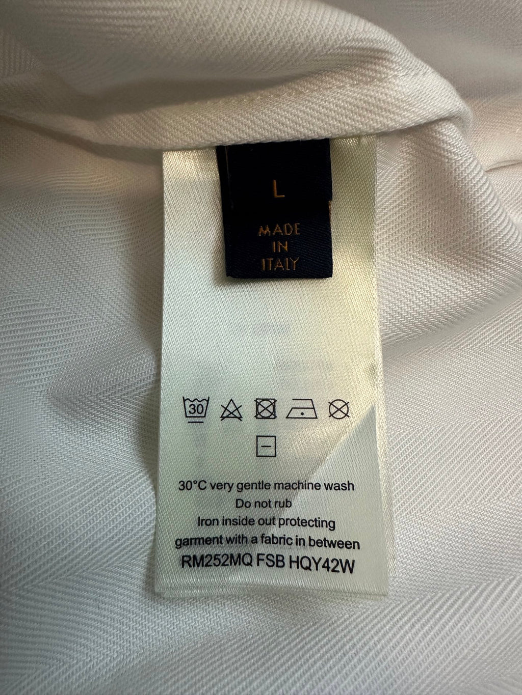 Black care label on white fabric with washing instructions and size info
