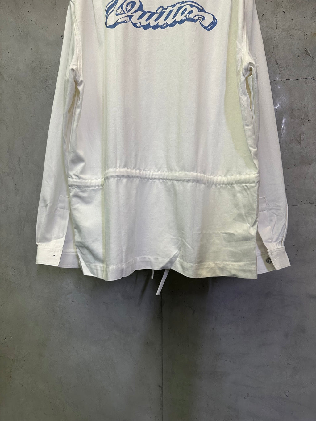 White long-sleeve jacket with blue back logo and gathered hem