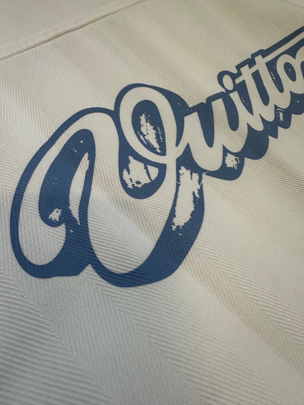 White fabric close-up with blue cursive logo print