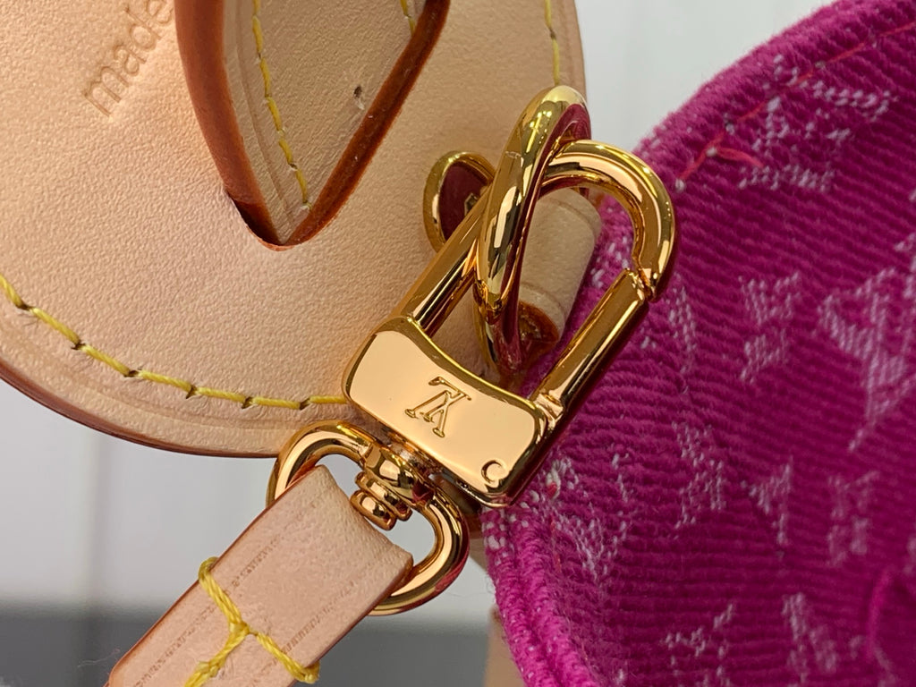 Tan leather strap end with gold-tone clasp on magenta monogram bag