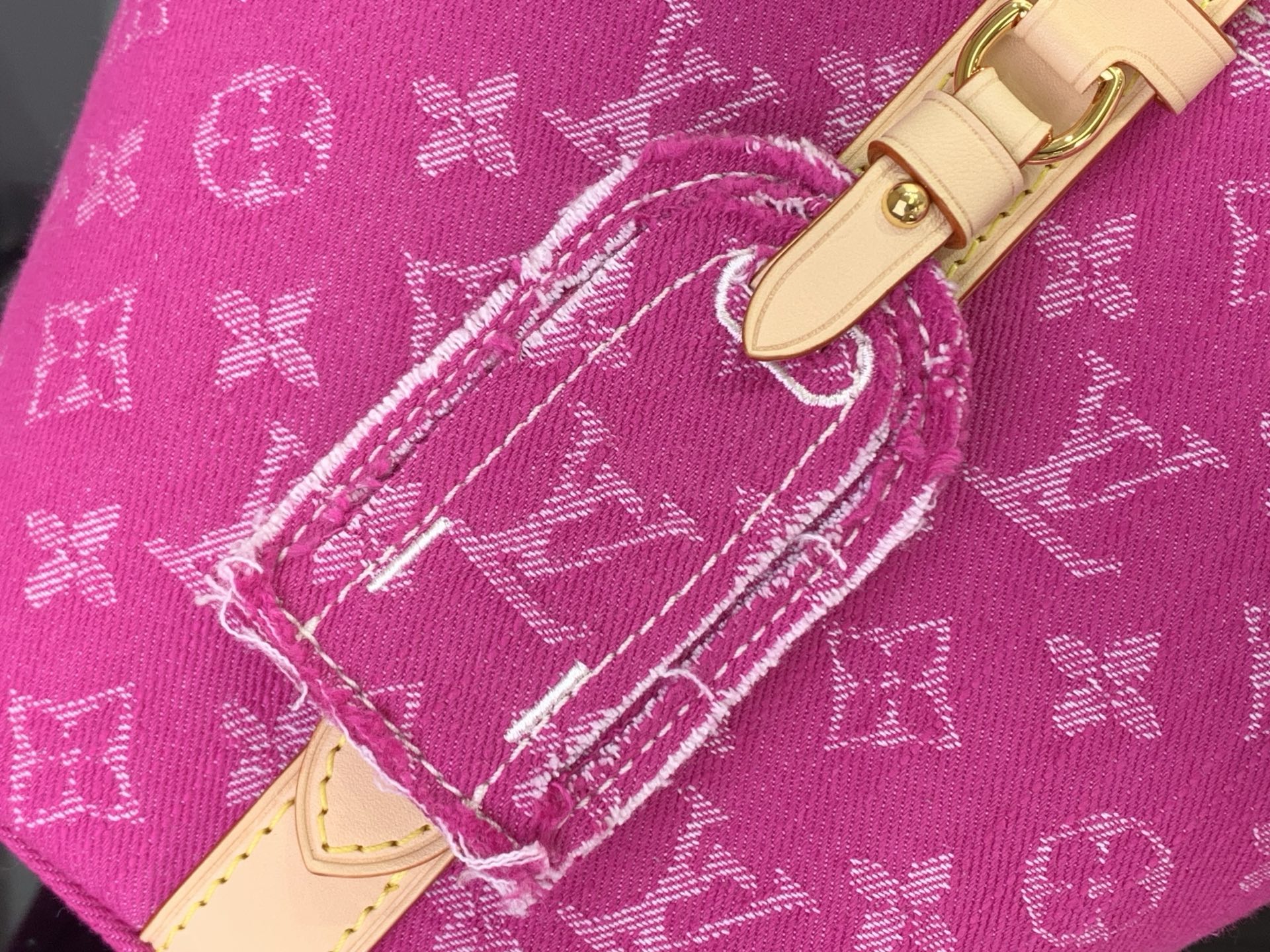 Magenta monogram tote corner with white stitching and tan leather strap detail