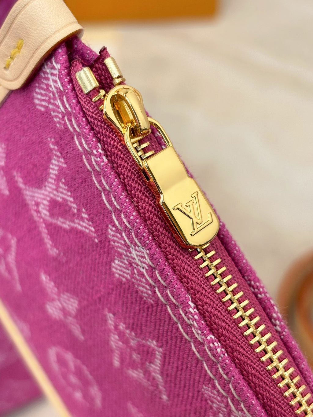 Gold zipper pull and hardware on purple monogram bag edge