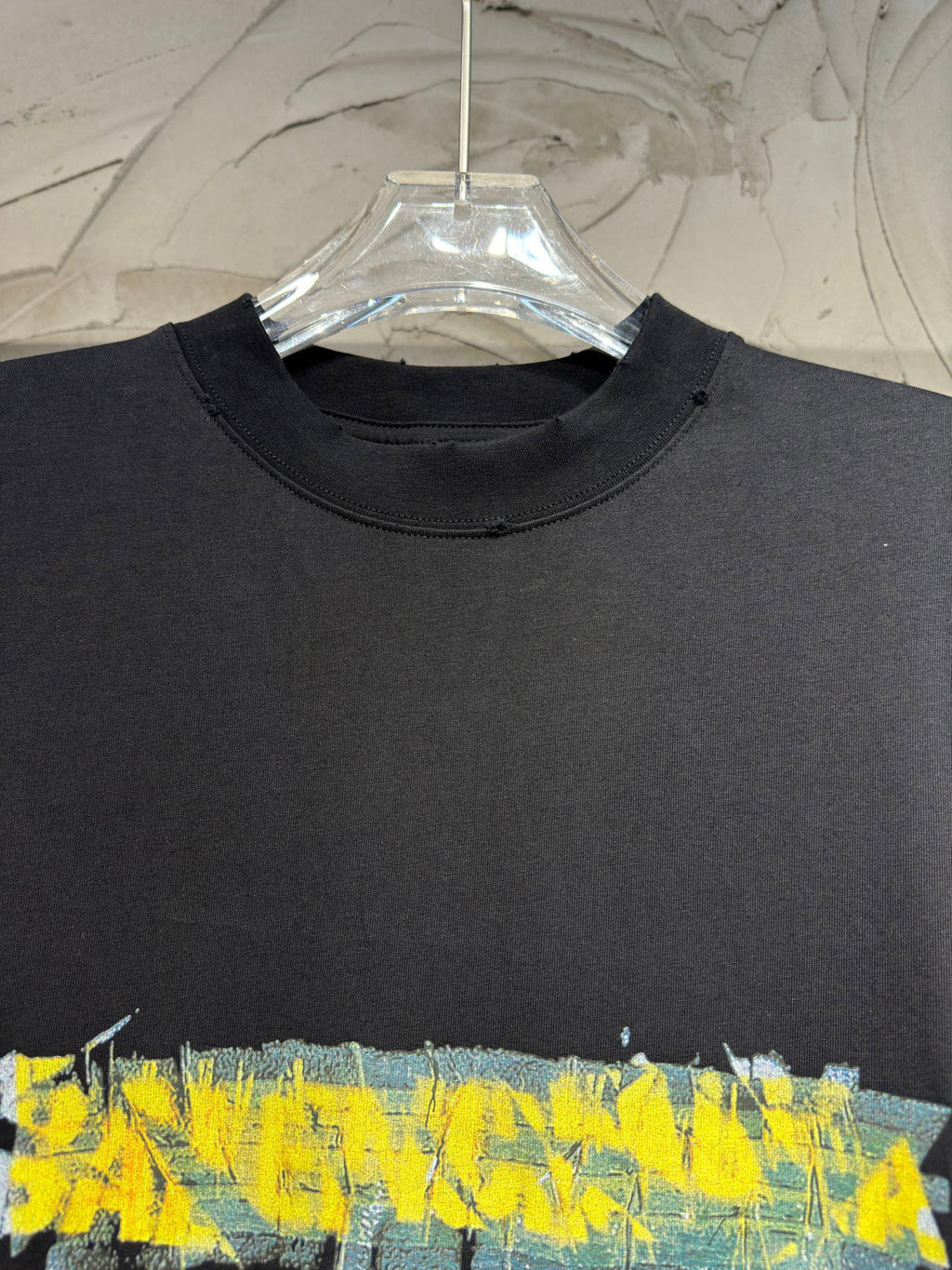 Black crewneck T-shirt with large yellow and blue paint-style graphic across chest